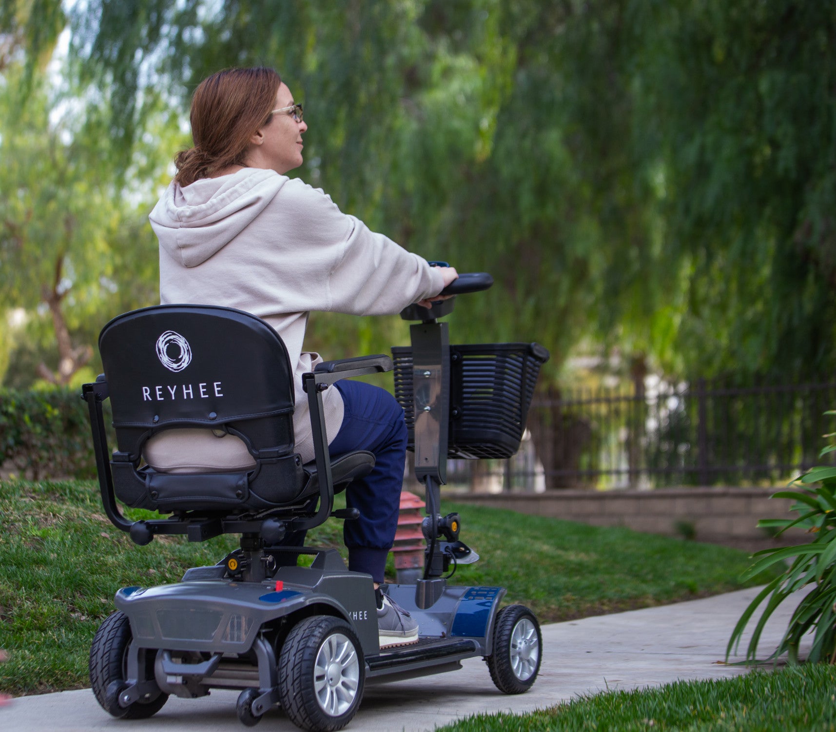 Back of a woman driving the blue Reyhee Cruiser mobility scooter outside on a sunny day
